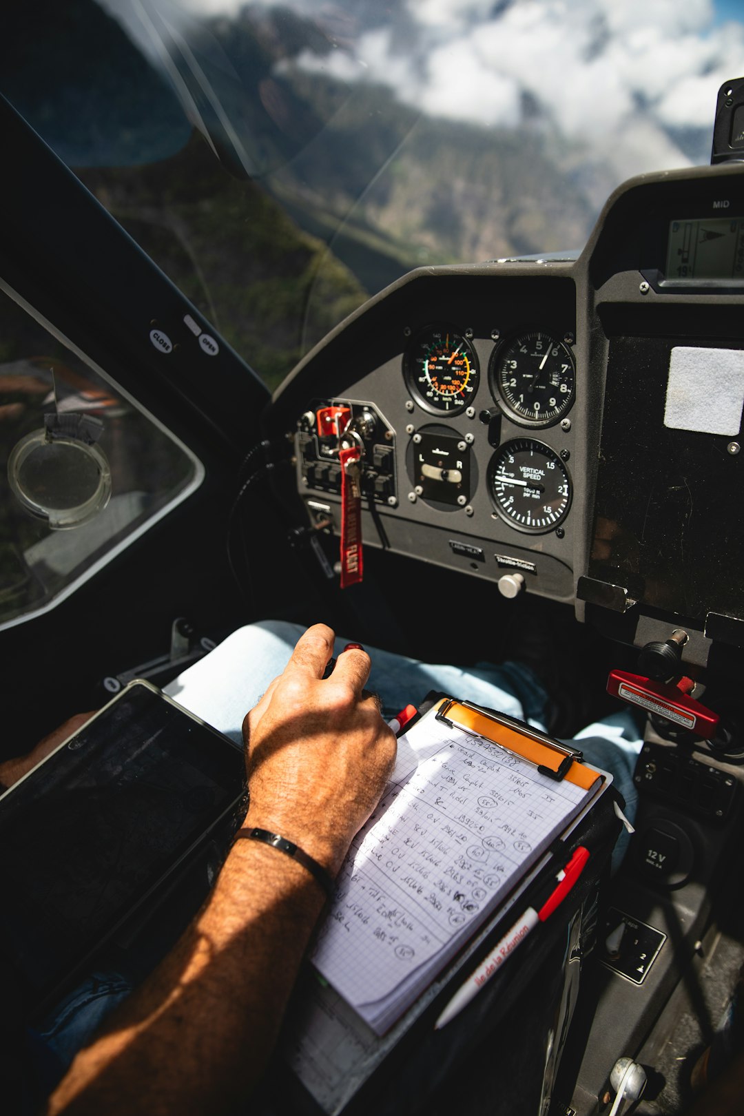 Pilot holding flight logbook and navigational checklist in cockpit